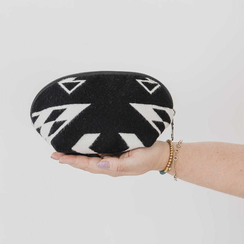 Black and white patterned pouch held by a hand on a light gray background