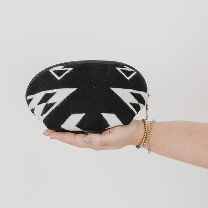 Black and white patterned pouch held by a hand on a light gray background